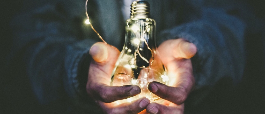 Person holding a lit lightbulb