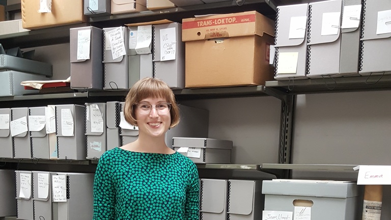 Anna Holland in front of shelves containing archival boxes